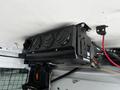 A black air conditioning unit mounted to the ceiling of a 2016 Ford Transit Connect with several air vents and connected hoses
