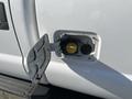 Close-up of the fuel filler door on a 2014 Ford F-350 SD showing a yellow fuel cap and the door slightly open