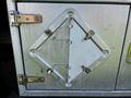 A silver metal storage compartment door featuring a diamond-shaped opening secured with hinges and multiple metal latches