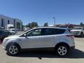 A silver 2014 Ford Escape is parked with its side facing the viewer showcasing its sleek design and alloy wheels