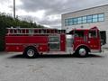 A red 1991 Sutphen Deluge fire truck with a ladder on top and various firefighting equipment visible on the side