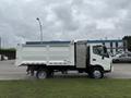 A white 2014 Hino 195 dump truck with a flatbed and a side door seen from the side angle