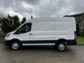 A white 2021 Ford Transit van parked on a street with no distinctive markings and equipped with black trim and silver wheels