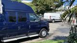 A blue 2013 Ford Econoline van parked in a lot with a raised roof and chrome side steps