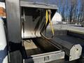 A metal storage box on the bed of a 2011 Ford F-350 SD with an open lid and a yellow strap inside