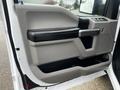 Interior door panel of a 2017 Ford F-150 featuring a gray and black design with a handle and control buttons