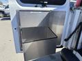 A metal storage compartment attached to the side of a 2007 Chevrolet Express van with a black interior section