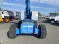 A blue 1997 Genie S-65 4X4 aerial lift with large tires and a boom arm extended upward