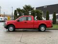 A red 2015 Ford F-150 pickup truck parked on a concrete surface with a standard cab and a long bed