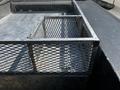 A metal mesh utility storage compartment attached to the bed of a 2008 Ford F-550 truck