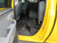Interior view of a 2015 RAM 1500 showing the driver's side door with a yellow exterior and gray fabric seats in the cabin along with a black floor mat and a console in between the seats