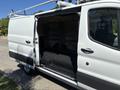 A 2016 Ford Transit van with an open side door revealing an empty cargo space equipped with a black floor and metal shelving mounts