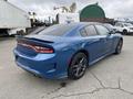 A blue 2022 Dodge Charger with a sleek design featuring a rear spoiler and black rims parked with a shiny exterior