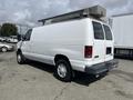 A white 2009 Ford Econoline van with sliding side doors and a roof-mounted storage unit