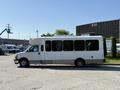 A 2017 Chevrolet Express bus with a white exterior and large windows parked on a street
