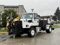 A 2016 Freightliner 108SD truck with a white body equipped with a front-mounted snowplow and a black attachment at the rear