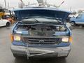 A blue 2006 Ford Econoline van with its hood open revealing the engine compartment and various components