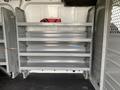 A 2017 Ford Transit van interior with multiple metal shelving units installed against one side of the cargo area