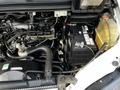 Engine compartment of a 2003 Mitsubishi Delica showcasing the engine components battery and coolant reservoir