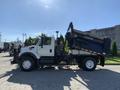 A 2007 International 7300 dump truck with a blue dump bed raised is displayed from the side