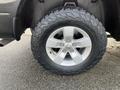 A close-up of a silver alloy wheel with a rugged tire on a 2015 RAM 1500