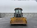 A 2011 John Deere 310SJ 4x4 wheel loader with an extended hoe and a 4 in 1 bucket positioned in the foreground