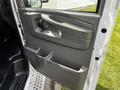 The interior door panel of a 2013 Chevrolet Express featuring a handle several control buttons and storage compartments