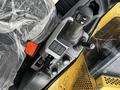Interior view of a 2024 Caterpillar 306 control panel featuring joysticks buttons and levers in a yellow and grey color scheme