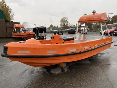 A bright orange 2008 Fassmer 20 Foot Fast Rescue boat with a flat bow and a covered helm is displayed on a wet surface