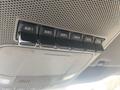 A row of six black auxiliary switches labeled AUX 1 through AUX 4 inside a vehicle's overhead console