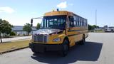 A yellow 2014 Freightliner Thomas diesel bus with multiple colored lights on the roof and black detailing on the front