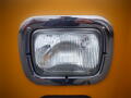 Close-up of a rectangular chrome-framed headlight on a yellow 2008 Freightliner MT45 Chassis