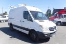 A 2012 Mercedes-Benz Sprinter van with a white exterior and orange lights on top parked at a commercial space