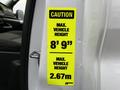 A caution sign on a vehicle door indicating maximum vehicle height of 8 feet 9 inches and 2.67 meters