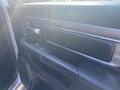 Close-up of the interior door panel of a 2021 RAM 1500 featuring a sleek design with controls for windows and locks, surrounded by black leather and brushed metal accents