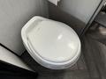 A white toilet seat with a modern design placed in a camper bathroom