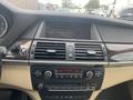 Dashboard of a 2009 BMW X5 featuring control dials for climate and audio settings along with a display screen showing radio information