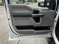 The interior door panel of a 2020 Ford F-350 featuring a gray and black design with a handle window controls and storage compartment
