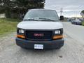 A white 2014 GMC Savana van is parked with a black front grille featuring the GMC logo and a visible license plate