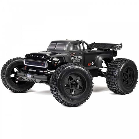 A black Arrma 1/8 NOTORIOUS 6S 4X4 RTR Brushless Stunt Truck with large rugged tires and a detailed body design showcasing various logos and features