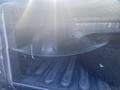 Interior of a 2021 RAM 1500 truck bed showing rough texture and a spare tire resting against the side