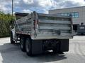 A white 2010 Freightliner M2 106 truck with a metallic dump bed showing its rear view and dual rear wheels
