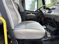 The interior of a 1998 Freightliner FL80 featuring a gray driver's seat with a sturdy design and various controls visible in the cabin