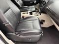 A black leather front seat of a 2017 Dodge Grand Caravan with armrests and a center console featuring cup holders
