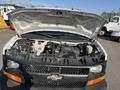 A 2014 Chevrolet Express with the hood open revealing the engine compartment and various components inside