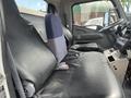 The interior of a 2008 Mitsubishi Fuso FE180 showing two large black leather seats and a blue upholstered driver's seat with controls and dashboard visible