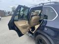 A 2009 BMW X5 with an open driver's side door revealing beige leather seats and interior features
