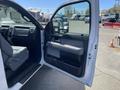 A 2012 Ford F-150 with an open driver's door revealing the interior features including the steering wheel and seats