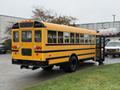 A yellow 2013 International 3000 school bus parked with its rear side visible and doors open