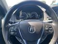 A close-up view of the steering wheel of a 2017 Acura TLX featuring controls for audio and cruise settings along with the Acura logo at the center
